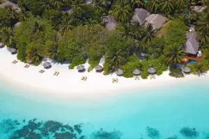 Luftaufnahme von Baros: Weißer Sandstrand, türkisfarbenes Wasser, Palmen und Bungalows mit Strohdächern. Ein tropisches Paradies.