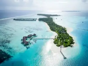 Luftaufnahme von Niyama Private Islands: Türkisblaues Wasser umgibt eine tropische Insel mit Villen auf Stelzen und üppiger Vegetation.