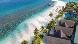 Luftaufnahme eines tropischen Resorts mit weißem Sandstrand, türkisblauem Meer, Palmen, Bungalows und Pool