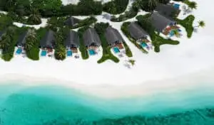 Luftaufnahme des Cora Cora Resorts mit luxuriösen Strandvillen, türkisfarbenem Wasser und weißem Sand. Palmen und üppige Vegetation säumen die Villen. Ein Paradies!