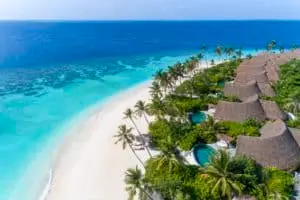 Luftaufnahme von Milaidhoo, Malediven: Türkisblaues Wasser, weißer Sandstrand, Palmen und luxuriöse Villen mit Strohdächern. Ein Paradies!