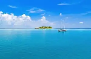 Segelboot vor Mirihi Island, türkisfarbenes Wasser und strahlend blauer Himmel mit Wolken. Luxuriöses Paradies bei V Villas Mirihi.