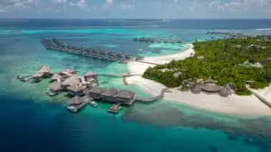 Luftaufnahme von Six Senses Laamu: Luxuriöse Wasserbungalows und üppige Vegetation auf einer tropischen Malediveninsel.