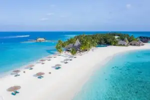 Luftaufnahme von Veligandu Island, Malediven, mit weißem Sandstrand, türkisfarbenem Wasser, Palmen und strohgedeckten Bungalows.