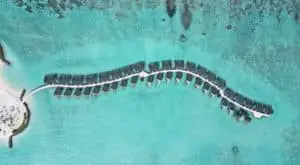 Luftaufnahme von Joy Island: Luxuriöse Wasserbungalows auf einer Privatfluginsel mit türkisfarbenem Wasser. Ein Paradies für exklusive Reisen.
