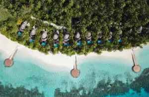 Luftaufnahme des W Maldives: Luxuriöse Strandvillen mit privaten Pools auf einer tropischen Insel, umgeben von türkisfarbenem Wasser und üppiger Vegetation.