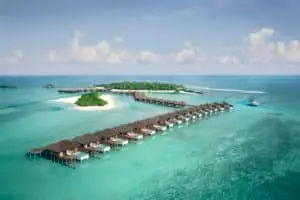 Luftaufnahme des Anantara Veli Resorts auf den Malediven: Luxuriöse Wasserbungalows mit privaten Pools über türkisfarbenem Wasser, verbunden mit einer grünen Insel. Ein Paradies für einen unvergesslichen Urlaub.