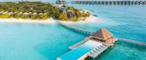 Luftaufnahme von Heritance Aarah: Türkisblaues Wasser umspielt eine Luxusinsel mit weißen Sandstränden, Villen und einem Steg zu einem Poolpavillon.