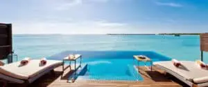 Luxuriöse Pool-Villa im Hideaway Beach Resort auf den Malediven. Türkisblaues Wasser trifft auf den Infinity-Pool, zwei Liegen laden zum Entspannen ein. Traumurlaub!