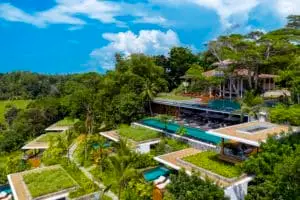 Luftaufnahme der luxuriösen HARITHA Villa mit Pools, üppigen Gärten und Dschungelblick unter blauem Himmel. Luxusresort-Architektur im Einklang mit der Natur.