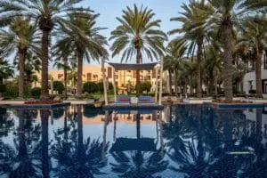 Pool im Park Hyatt Abu Dhabi, gesäumt von Palmen, die sich im Wasser spiegeln. Luxushotel mit Privatstrand & erstklassigem Service.