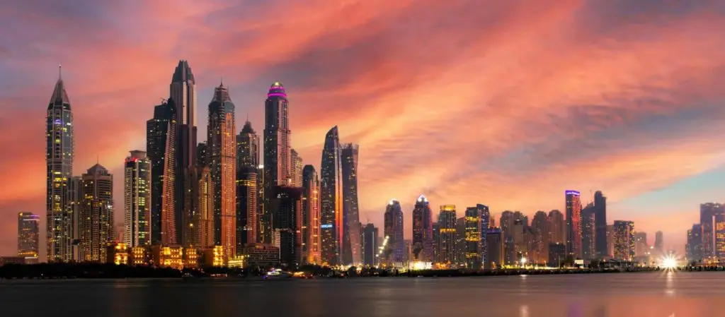 Dubai Skyline bei Sonnenuntergang: Wolkenkratzer in warmen Farben spiegeln sich im Wasser. Moderne Architektur trifft auf arabische Traditionen.