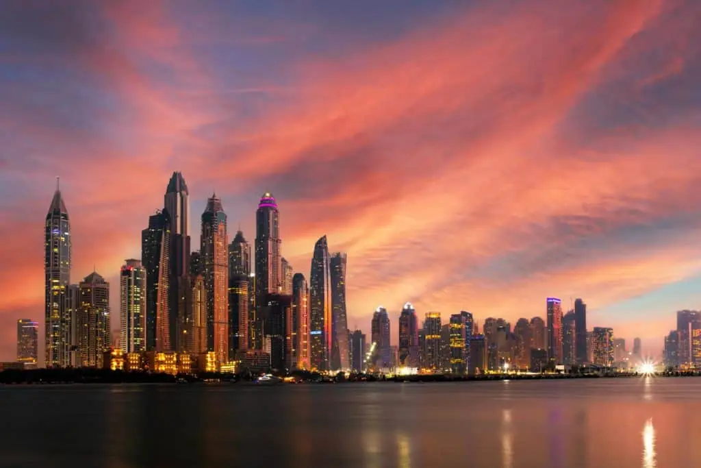 Dubai Skyline im Abendrot: Moderne Wolkenkratzer spiegeln sich im Wasser, ein faszinierender STOP OVER zwischen Tradition und Moderne. Entdecken Sie Dubai!