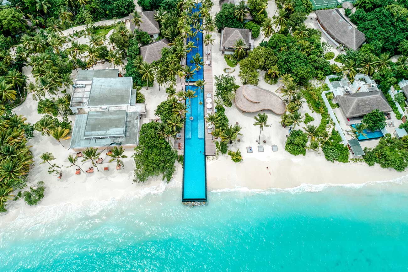 Luftaufnahme eines tropischen Strandresorts mit langem Pool bis zum Meer