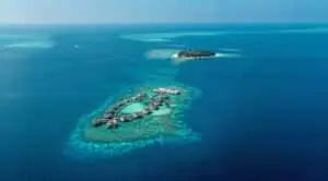 Luftaufnahme eines tropischen Inselresorts mit Wasserbungalows über einem Korallenriff