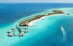 Luftaufnahme einer tropischen Insel mit Resort, weißen Stränden und über dem Wasser gebauten Bungalows