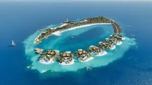 Luftaufnahme einer tropischen Insel mit Resort, Villen, Stegen und Segelbooten im türkisblauen Meer auf den Malediven