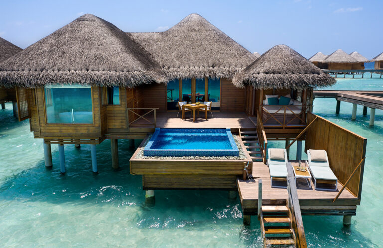 Überwasserbungalows mit Strohdächern, privatem Pool und Liegestühlen über türkisfarbenem Meer