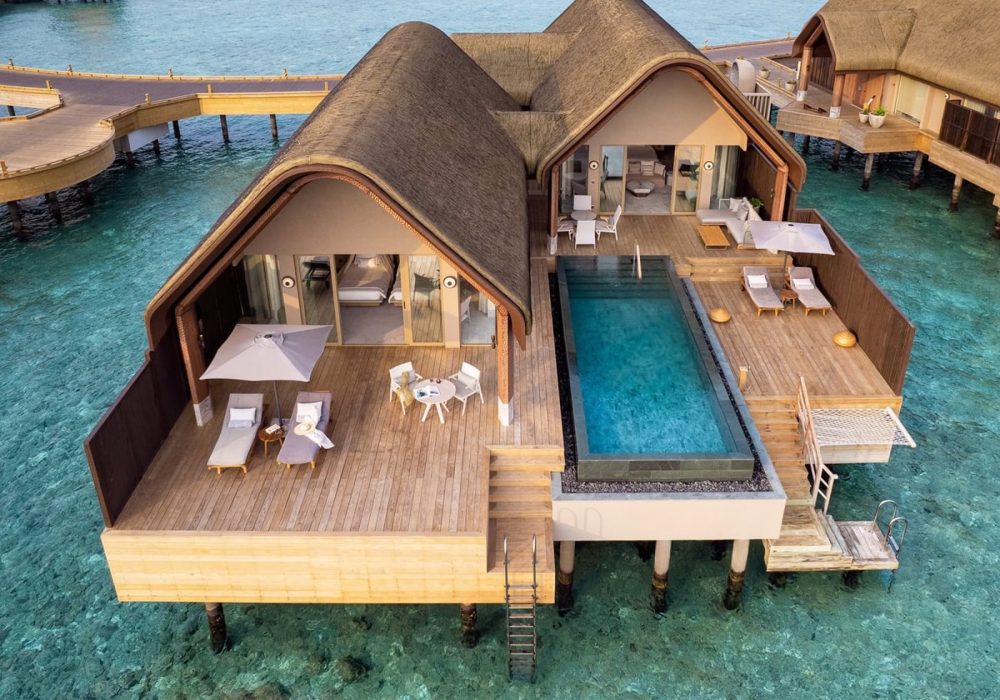 Luxuriöse Joali Being Wasservilla mit privatem Pool und Holzterrasse über türkisfarbenem Wasser. Exklusives Resort-Erlebnis.